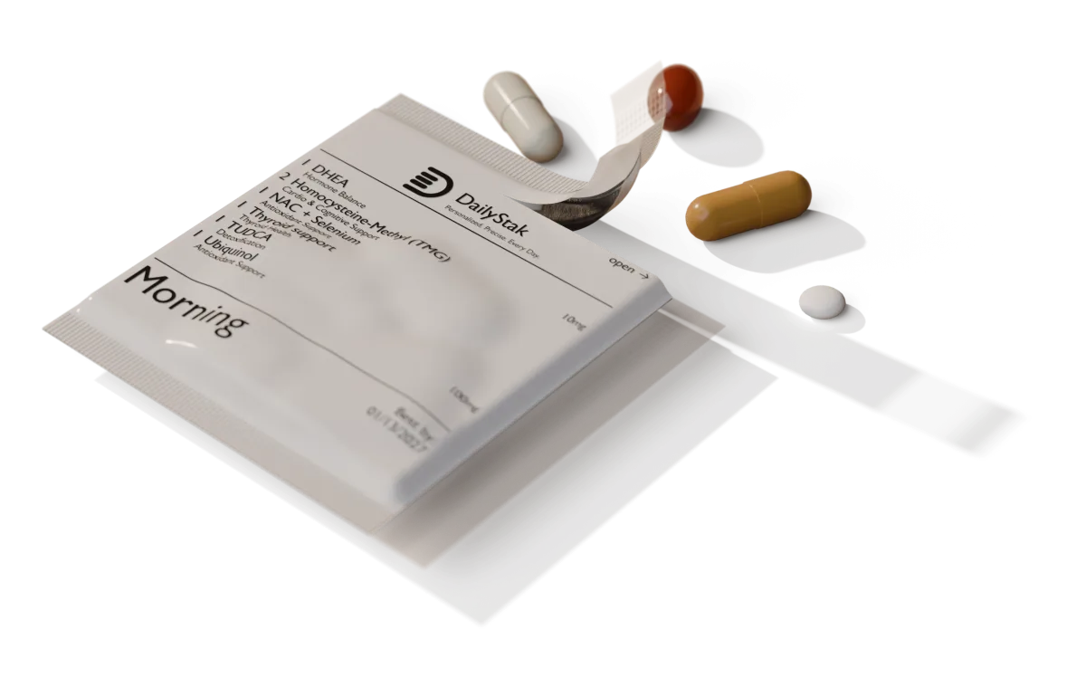 A DailyStak morning pack torn open at the corner, with its capsules and a tablet beside it